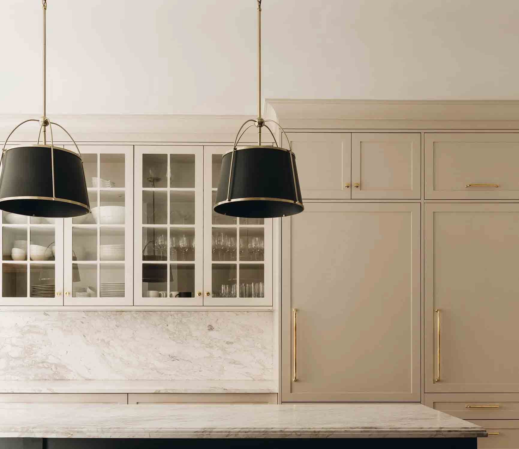 Elegant kitchen with cream cabinets, marble backsplash, and two black pendant lights over a pale countertop