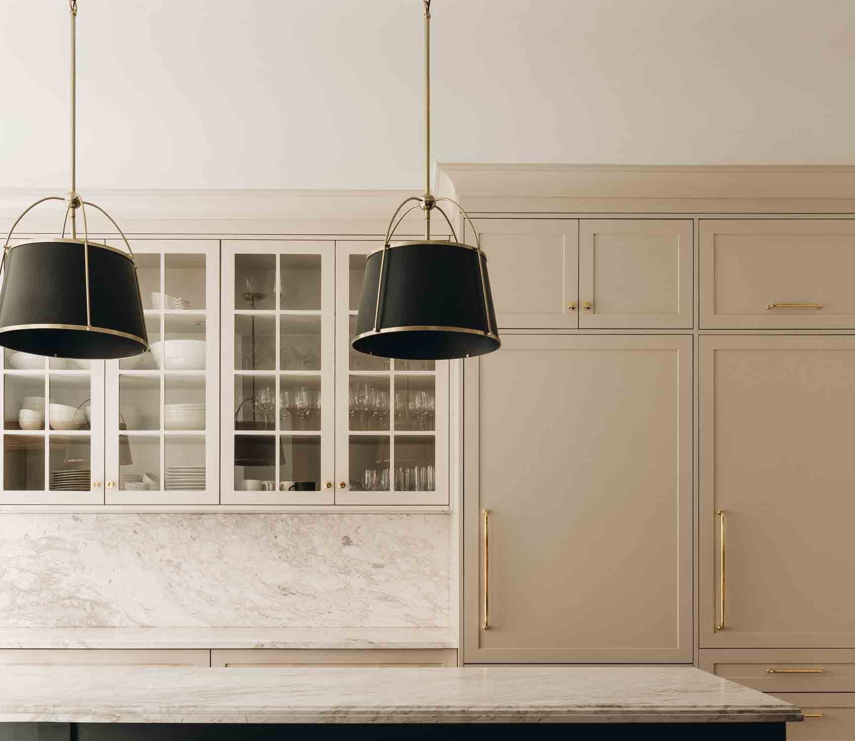 Modern beige kitchen with glass-front cabinets and two black pendant lights over a marble island