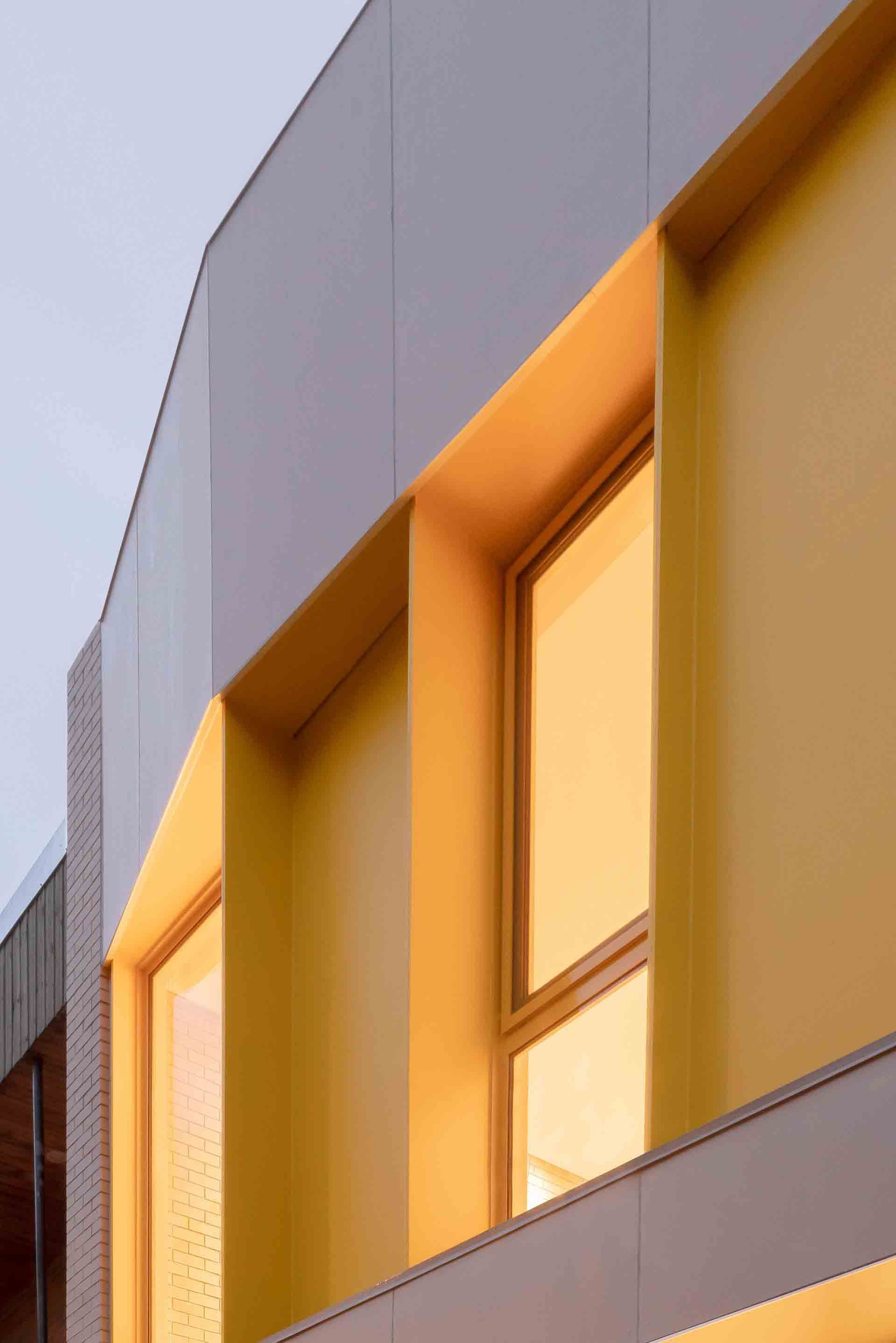 Façade d'immeuble moderne avec fenêtres jaunes et panneaux gris