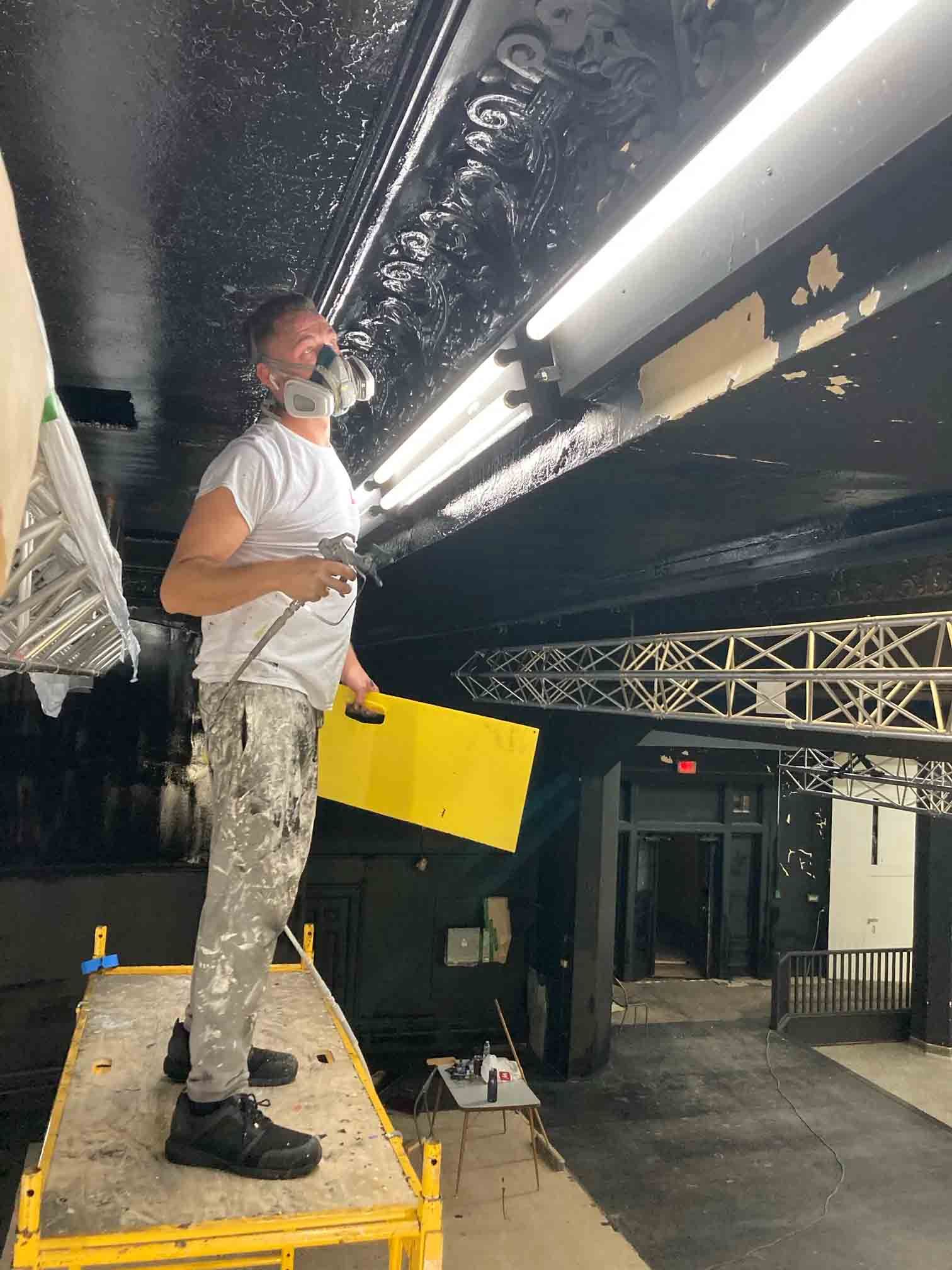 Worker standing on a platform inspecting the ceiling lights inside a dark venue