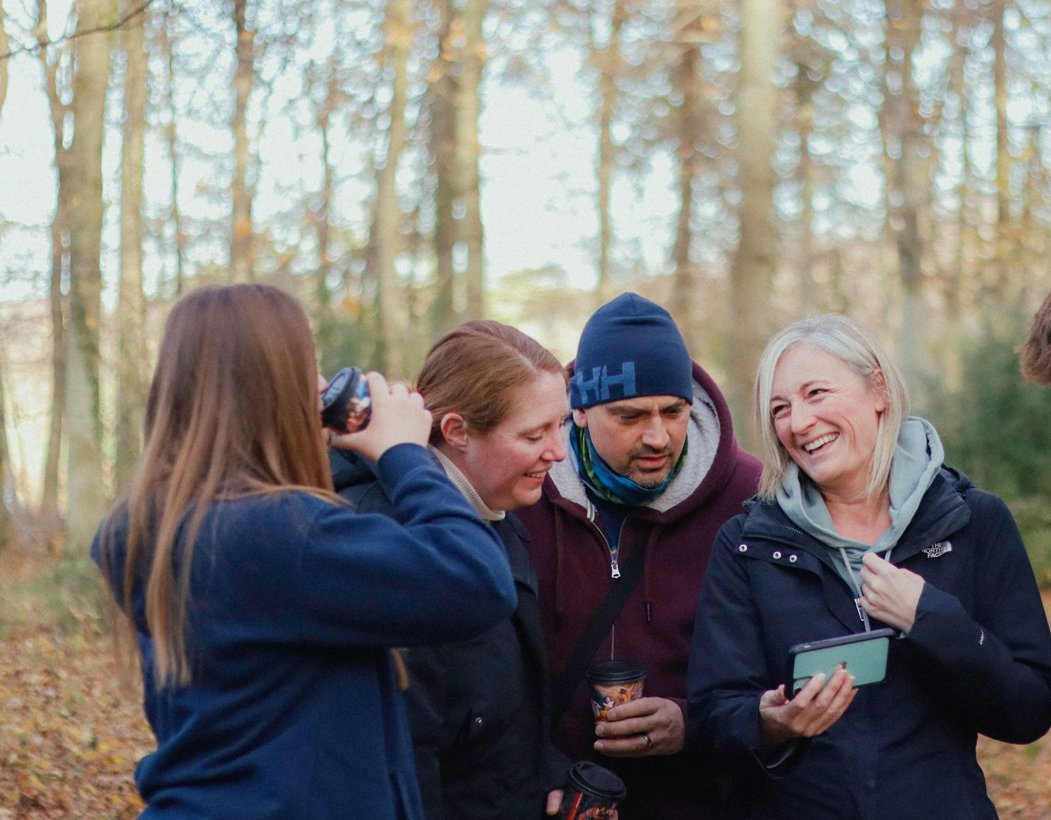 Group of friends walking on a road through a forest, talking and smiling.