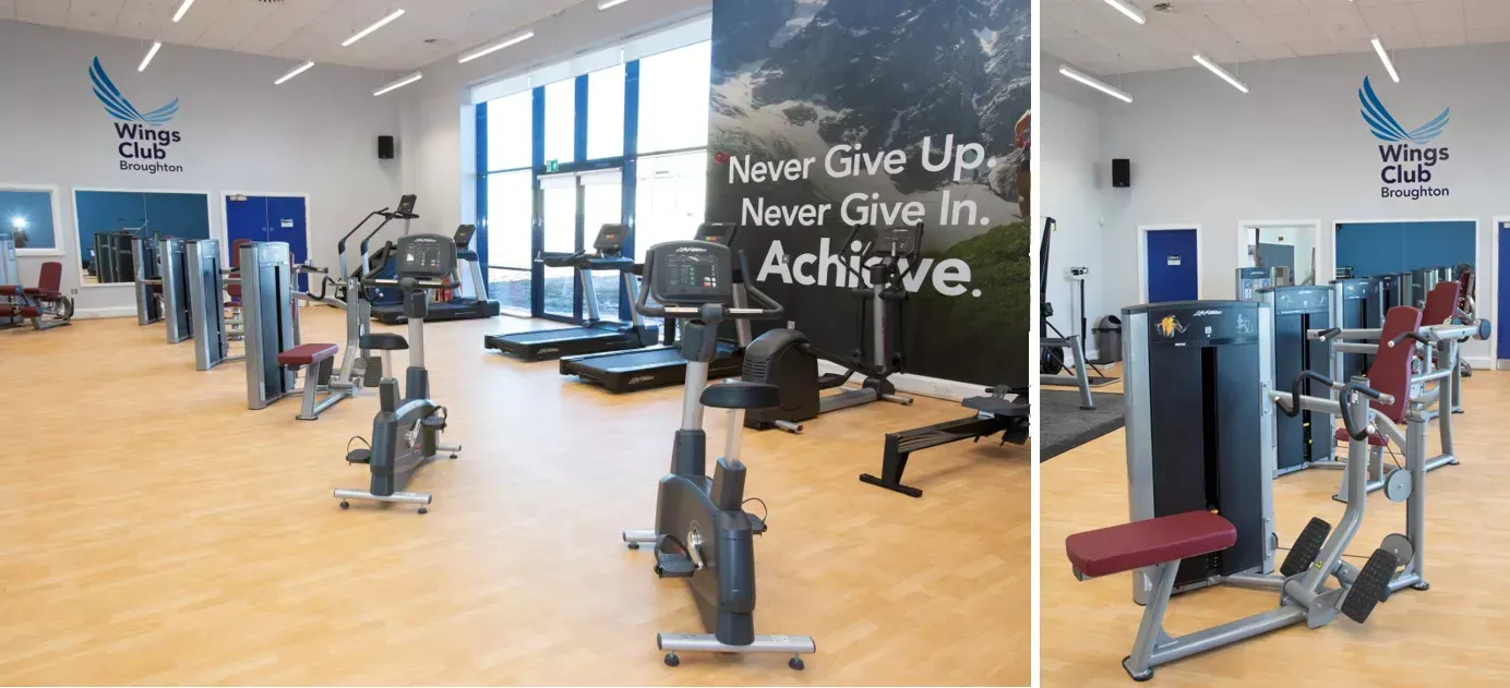 Gym interior with exercise machines, including treadmills and stationary bikes. Motivational text on wall.