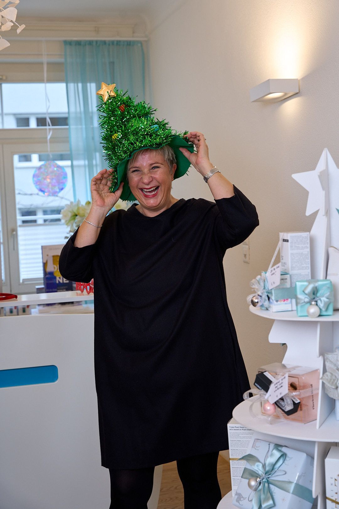 Frau setzt sich einen Weihnachtshut auf und lacht.