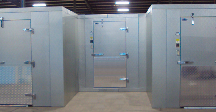 Three walk-in cooler/freezer units with metal doors in a warehouse setting.