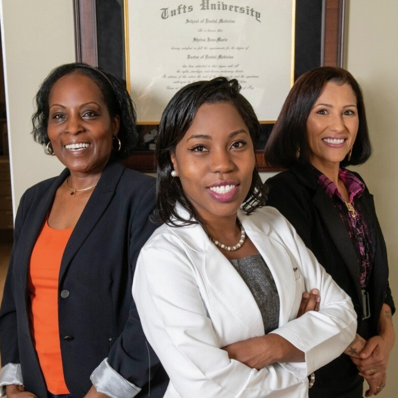 Three women are posing for a picture in front of a tuffs university diploma