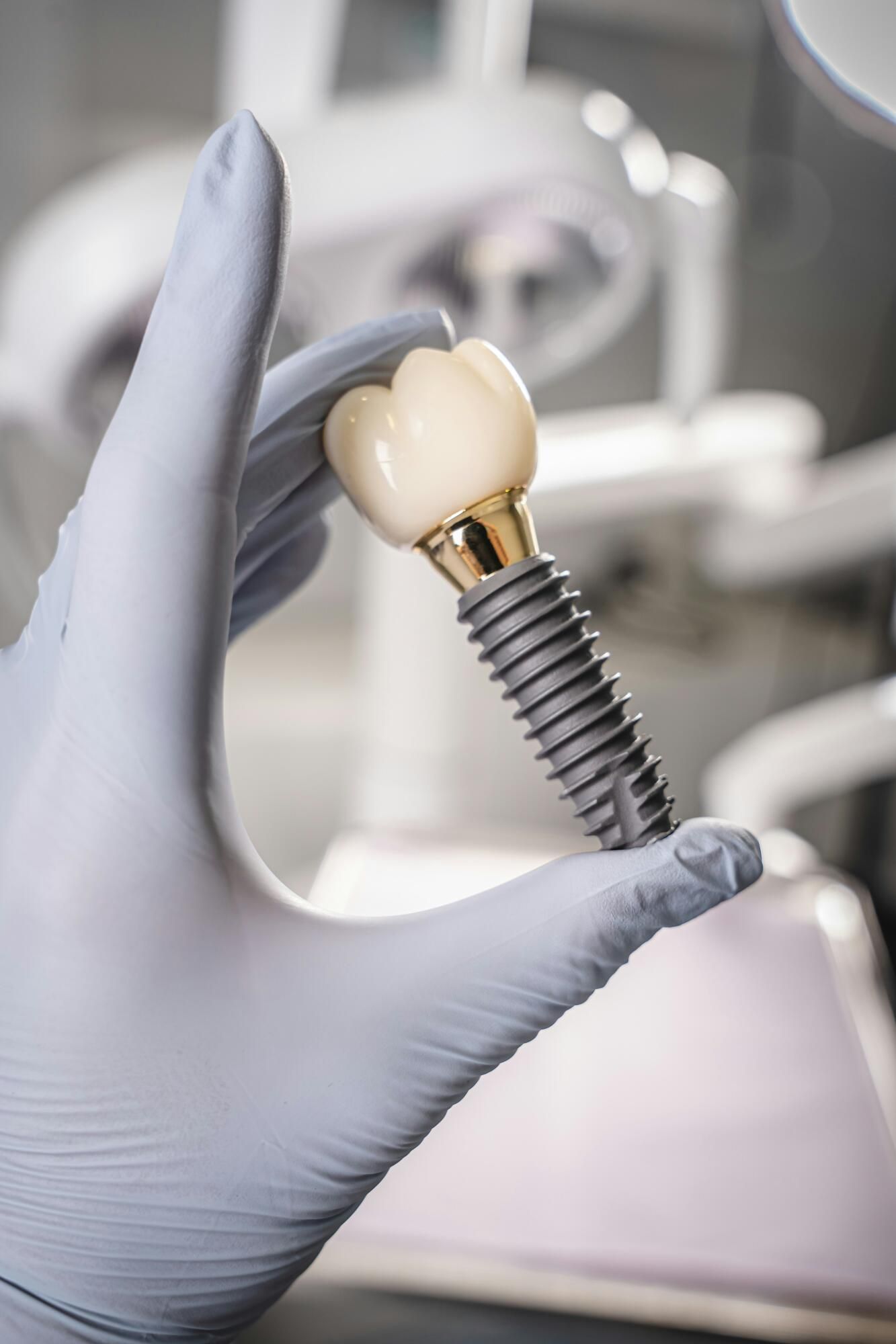 Gloved hand holding a dental implant crown in a clinic setting