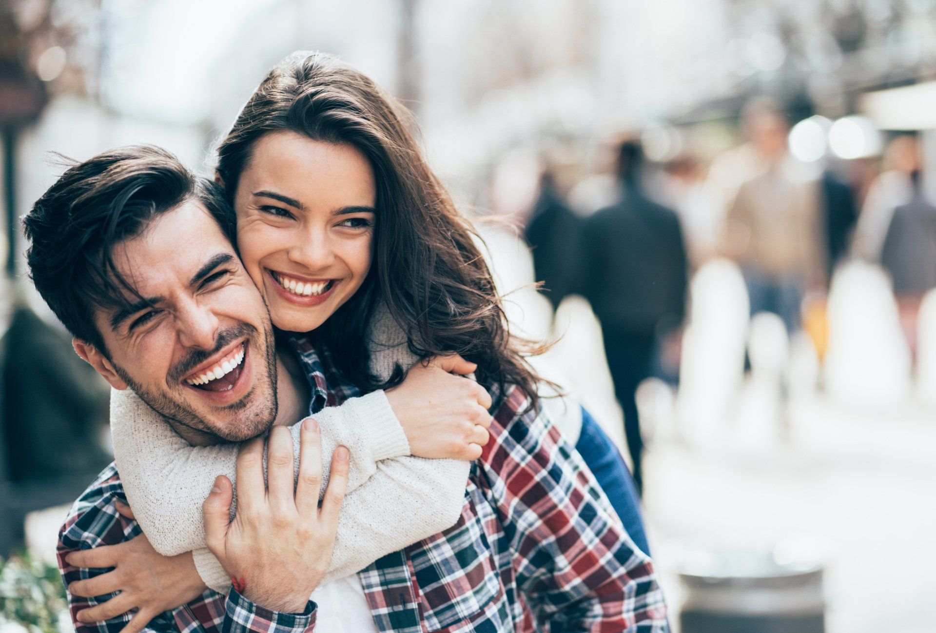 A man is carrying a woman on his back and they are smiling.