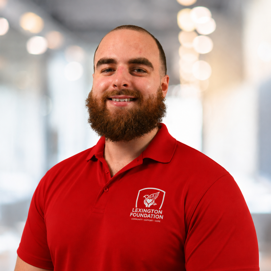 Man with beard wearing a red polo shirt with Lexington Canine Academy logo, smiling.