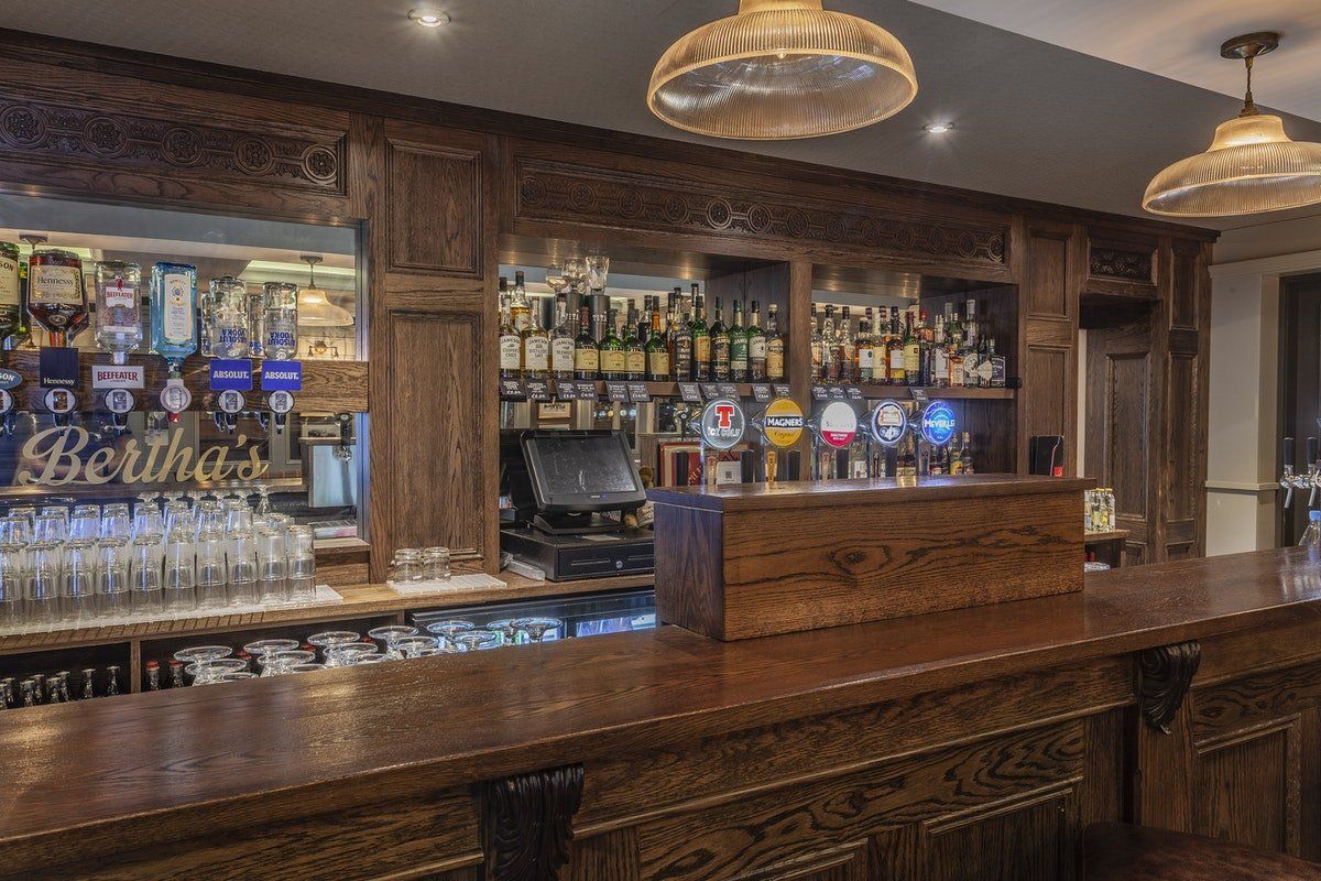 Wood-paneled bar with taps, bottles, and hanging pendant lights in a cozy pub interior