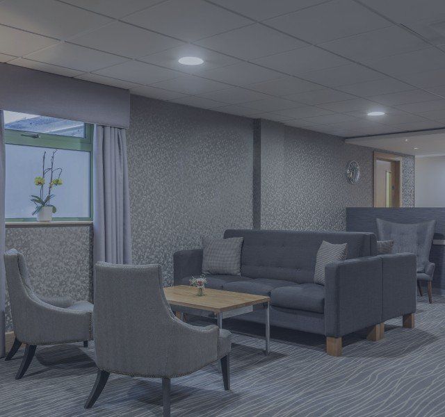 Modern lounge with gray sofas, armchairs, and a coffee table under soft ceiling lights