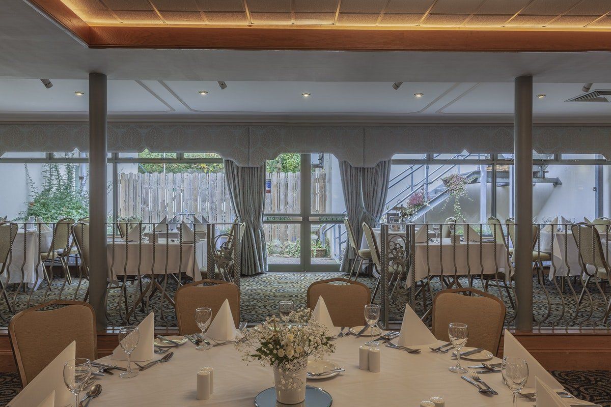 Elegant dining room with set tables, upholstered chairs, and large windows overlooking a waterfront view