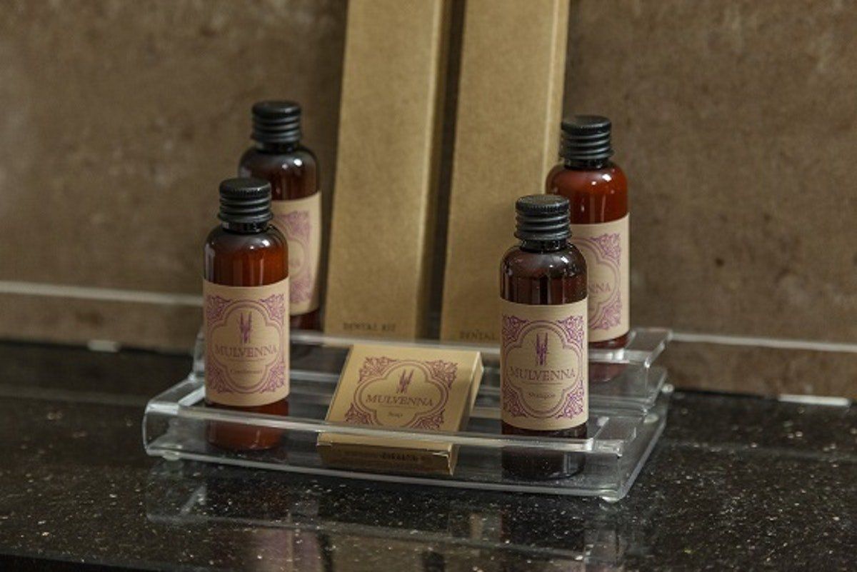 Three amber bottles and a soap bar on a clear tray beside a sink
