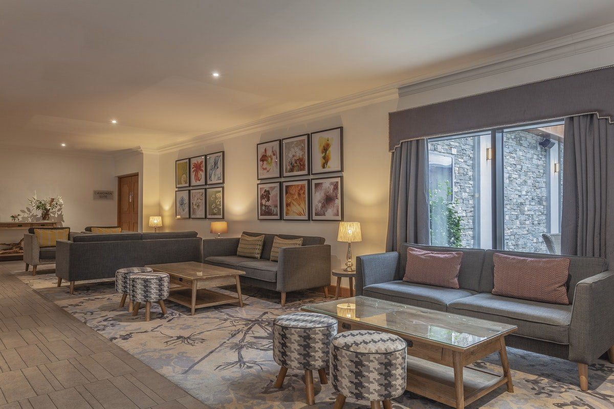Modern hotel lobby with gray sofas, patterned rugs, wall art, and large windows