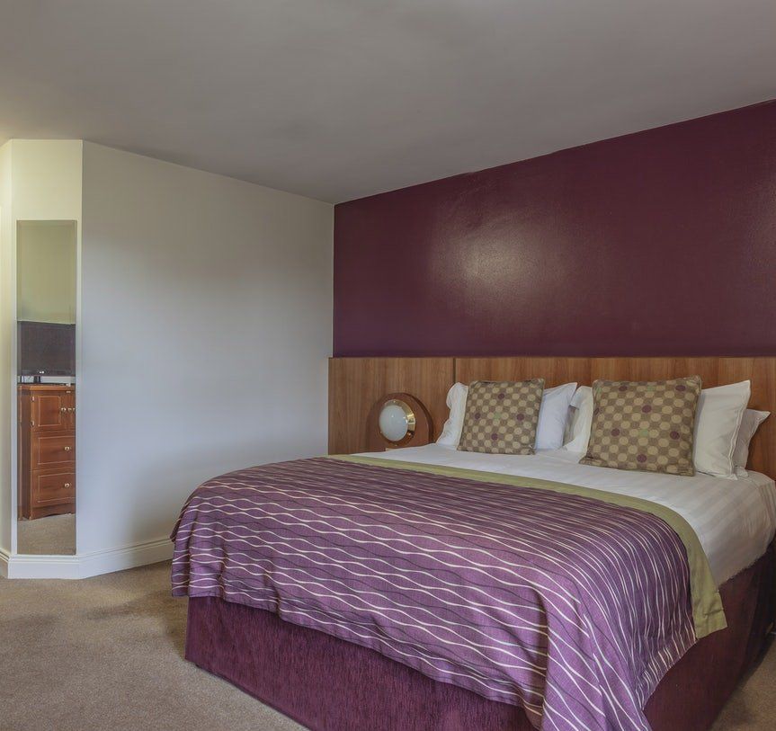 Modern bedroom with purple accent wall, king bed, and purple striped bedding