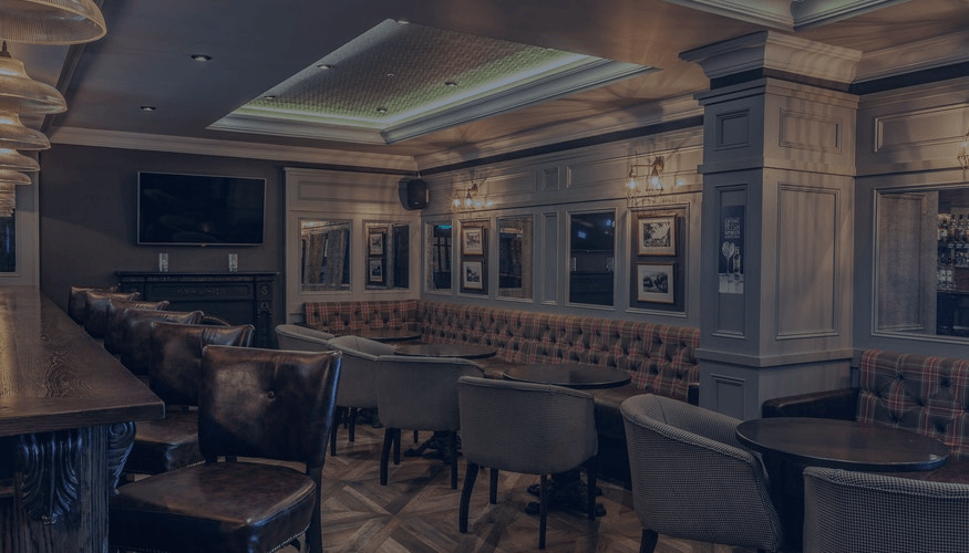 Elegant restaurant lounge with tufted banquettes, framed art, and cozy seating under warm recessed lighting