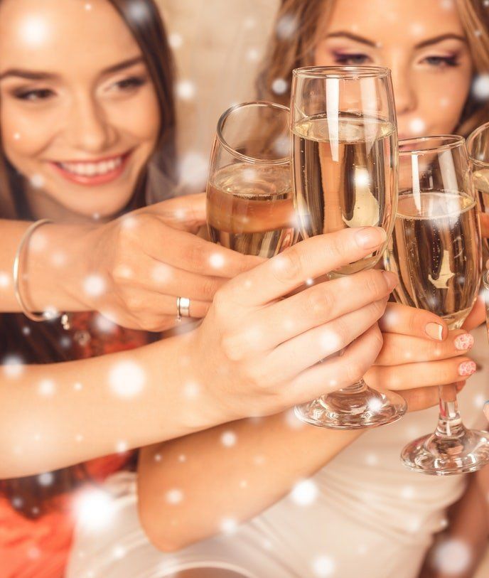 People clinking champagne glasses at a festive celebration, smiling under warm lights