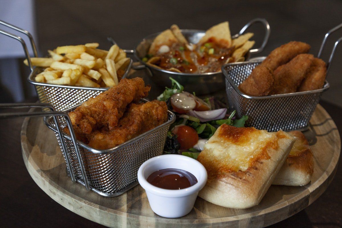 Assorted fried appetizers with fries, dip, and bread on a wooden serving tray