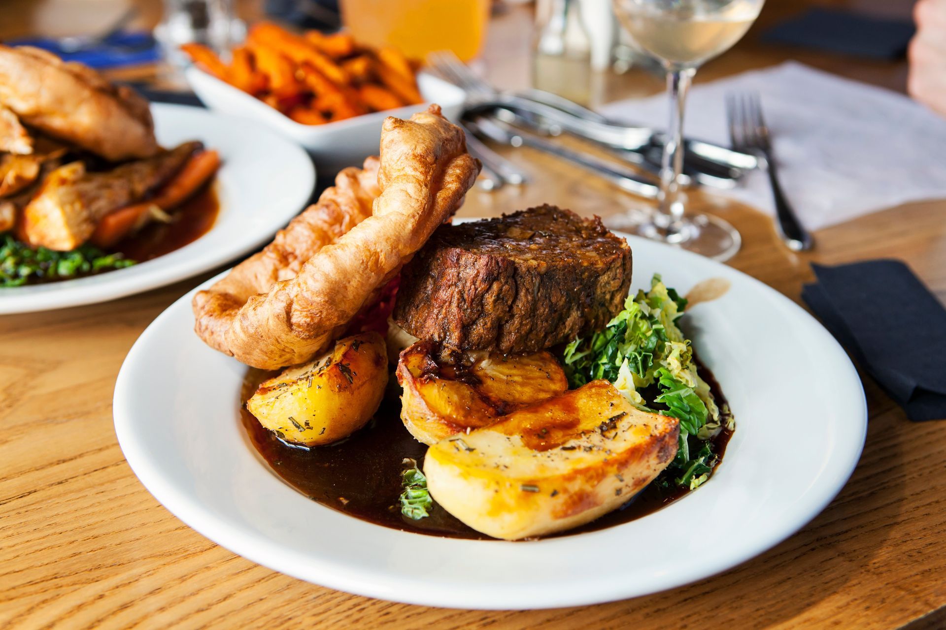 Plated roast dinner with steak, sausage, potatoes, and vegetables on a restaurant table