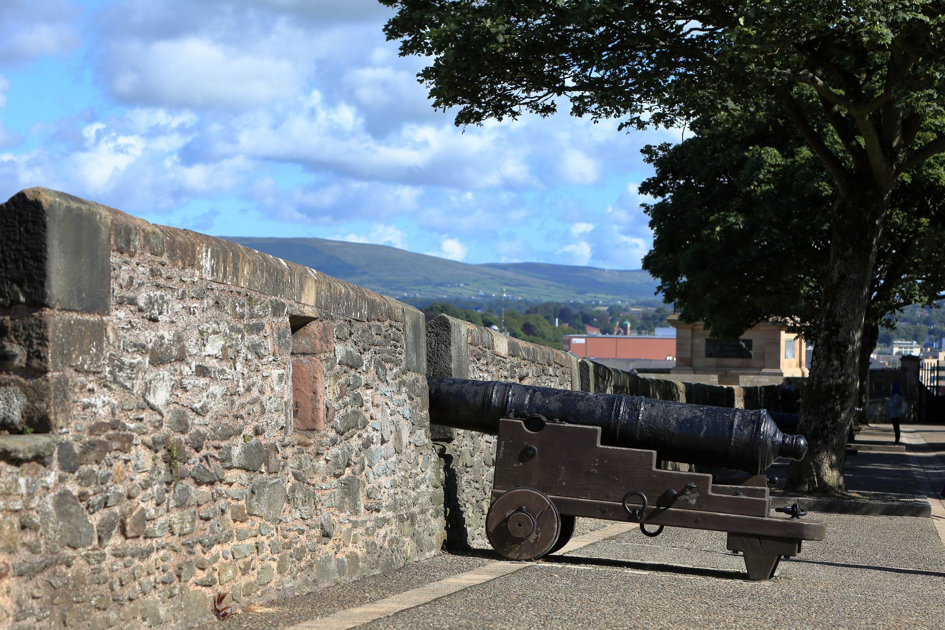 Stone fortress wall with old cannon overlooking a sunny mountain landscape