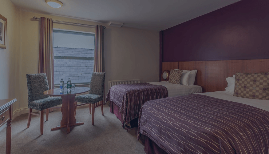Hotel room with two twin beds, a window view, and a small table by two chairs