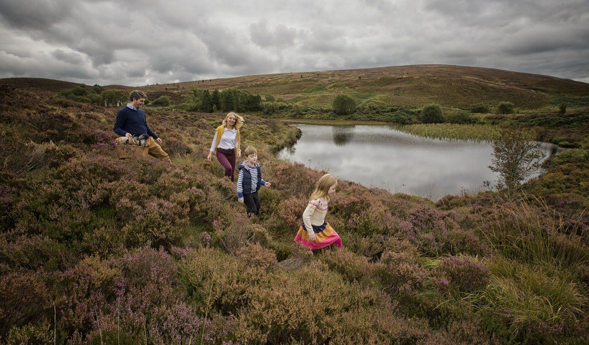 Hikers crossing a moor beside a small lake under an overcast sky