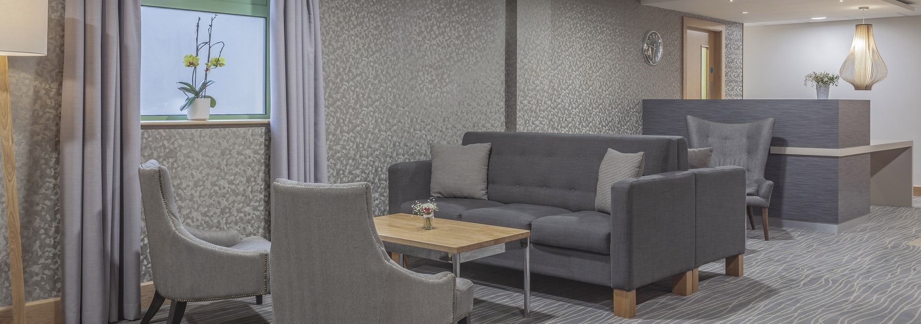 Modern living room with gray furniture, round coffee table, window, and fireplace mantel