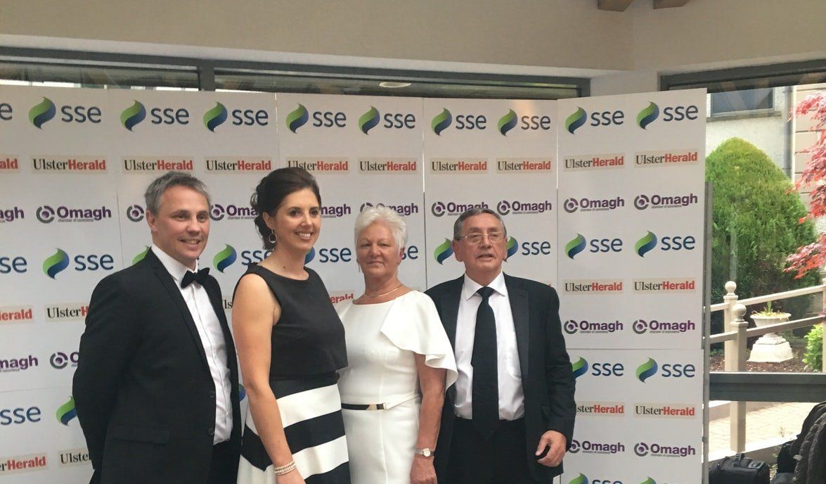 Four people posing in front of an SSE-branded backdrop at a formal event.