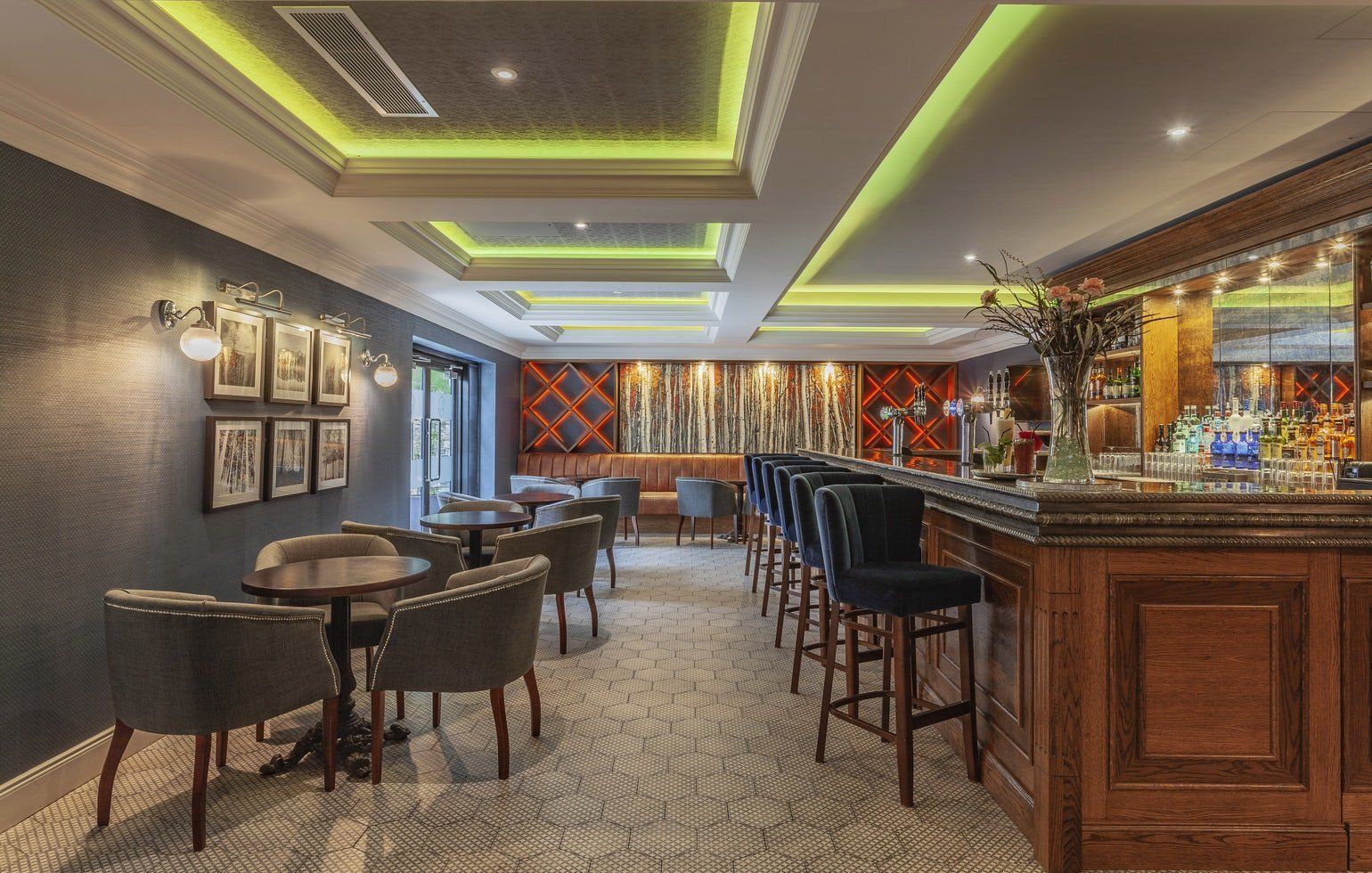 Elegant bar lounge with tables, chairs, wood counter, and warm ambient lighting