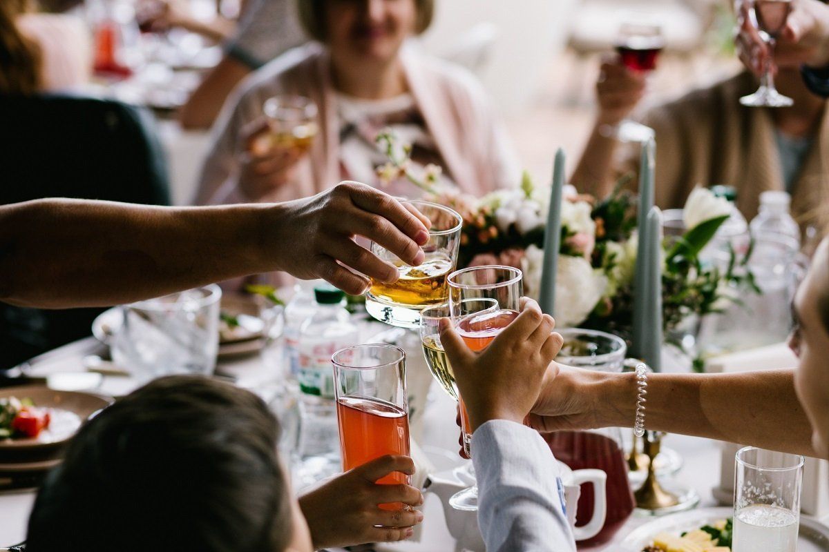 Friends raising drinks in a toast at a dinner table with candles and flowers