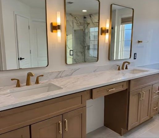 Large master bathroom in Westminster with freestanding tub, heated floors, double vanity with makeup space, large shower tile, brushed gold mirrors, and sconces