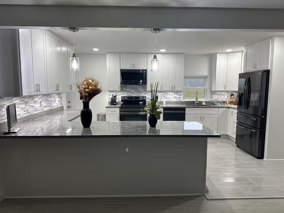 Kitchen remodel in Finksburg with wall removed for open concept, peninsula with 42-inch wall and overhang, white shaker cabinets, and tile flooring