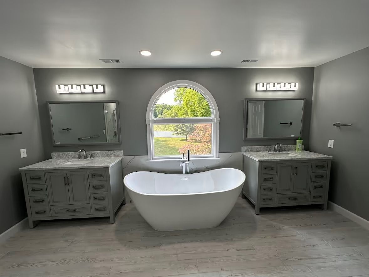 Extra-large master bathroom in Finksburg with freestanding tub under arched window, two 48-inch vanities, and large walk-in shower with bench