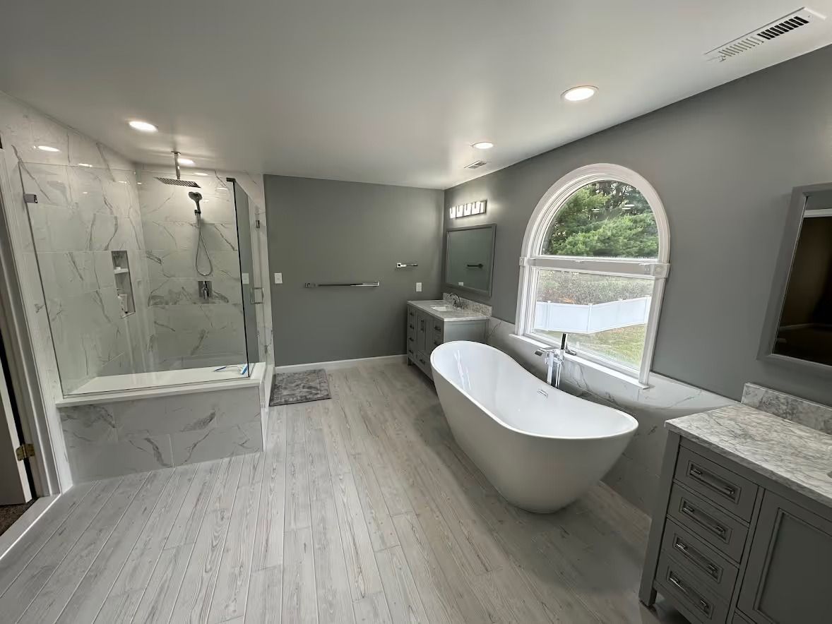 Extra-large master bathroom in Finksburg with freestanding tub under arched window, two 48-inch vanities, and large walk-in shower with bench