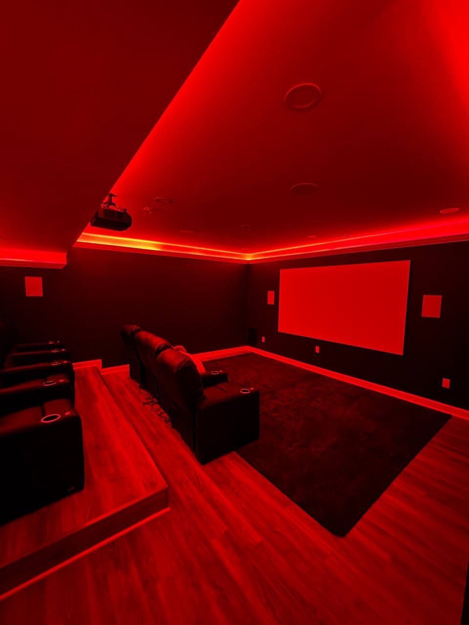Home movie theater remodeling in Finksburg featuring LED lighting installed under crown molding for an elegant ambient glow, creating a modern cinematic atmosphere with comfortable seating and custom wall finishes.
