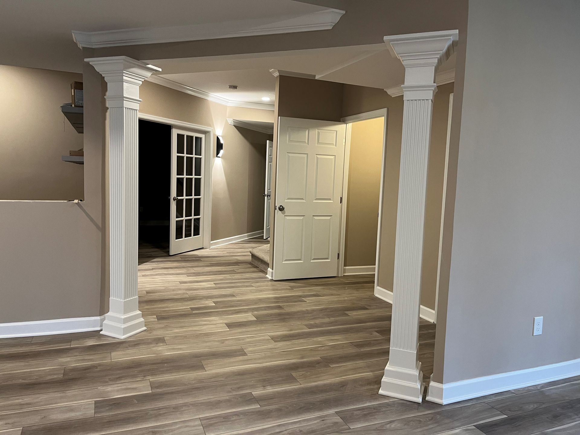 Finished basement in Finksburg with LVP flooring, U-shaped wet bar, stacked stone fireplace, French glass doors, bedroom, gym, and bathroom