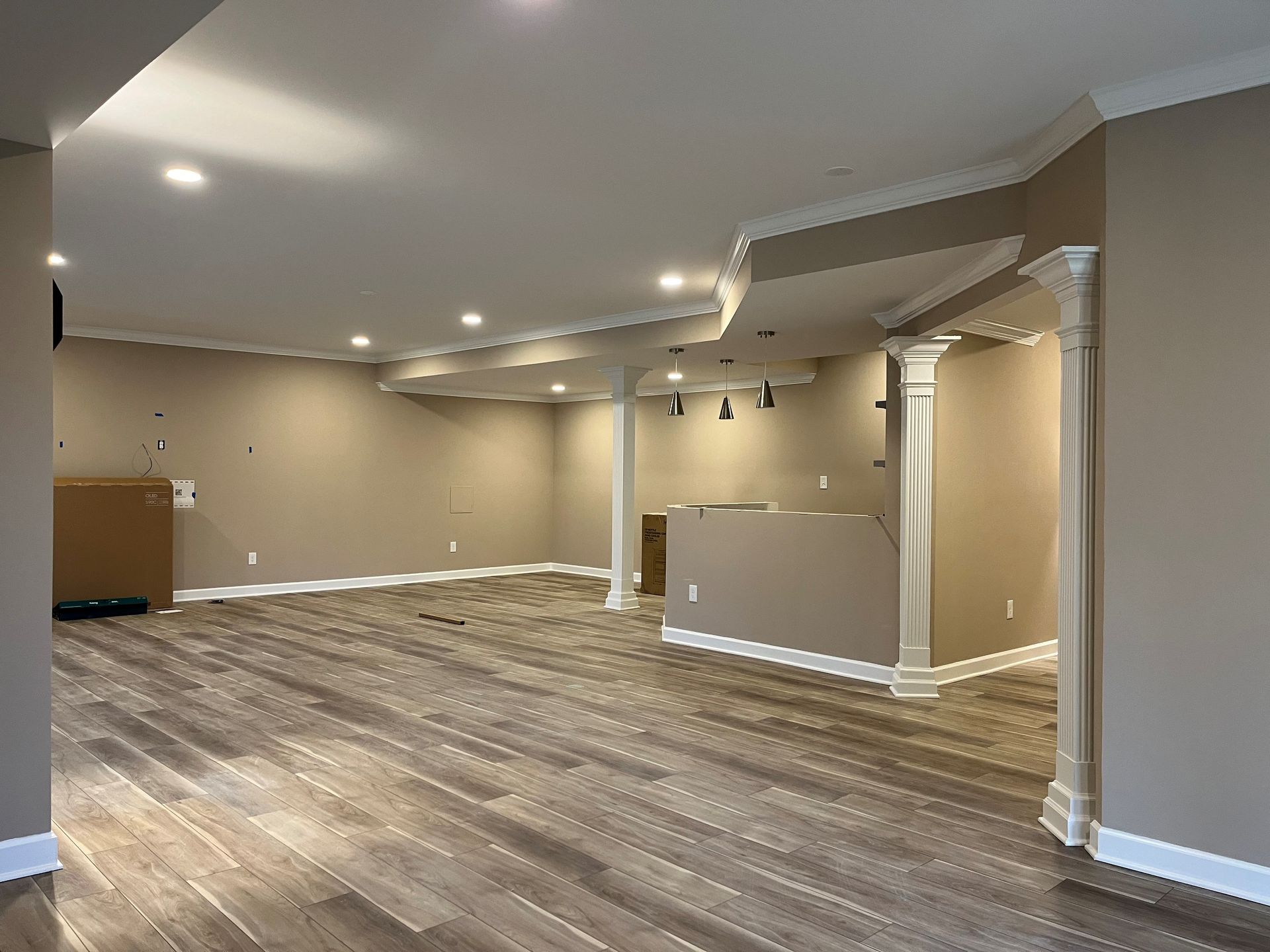 Finished basement in Finksburg with LVP flooring, U-shaped wet bar, stacked stone fireplace, French glass doors, bedroom, gym, and bathroom