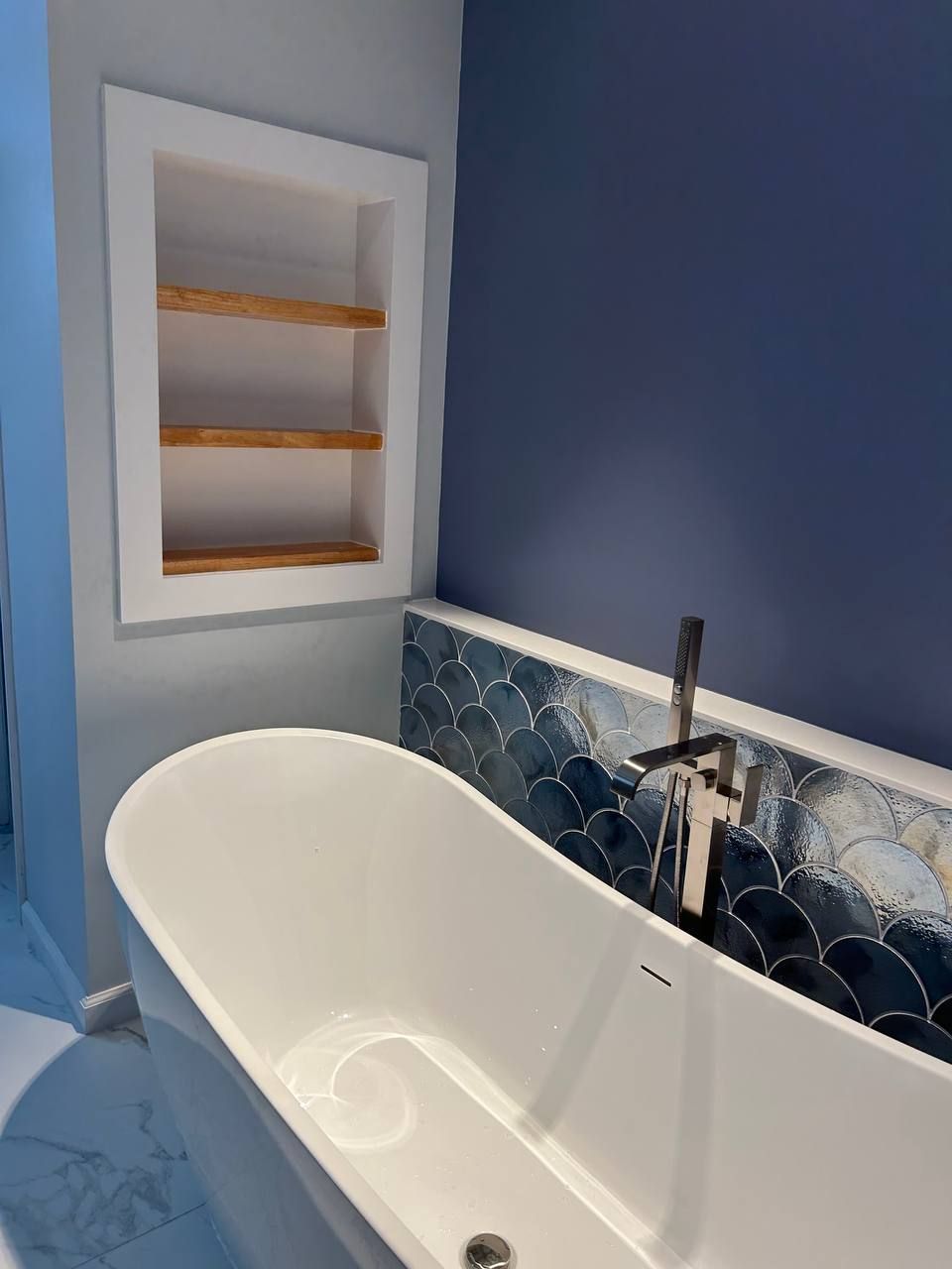 Elegant white powder room featuring a floating vanity with bowl sink, LED mirror with sconces, one-piece toilet, vein-patterned wall coating, brushed gold trim, and hardwood flooring