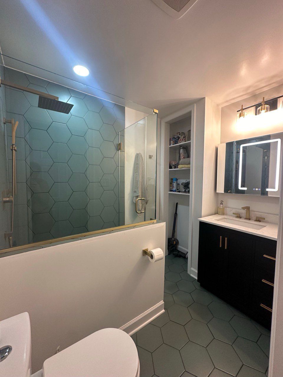 Green tile shower in Baltimore City with half wall, frameless custom glass, handheld fixture, and 8-inch hexagon tile on walls and floor