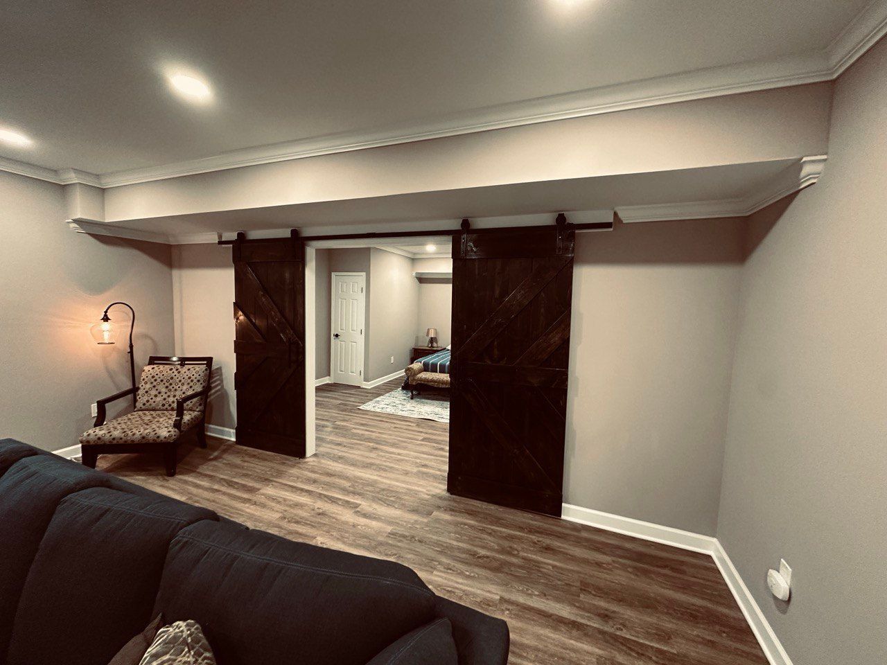 Finished basement bathroom with luxury vinyl plank flooring, sliding barn door, custom corner shower, and space-saving layout.in Hunt Valley, MD