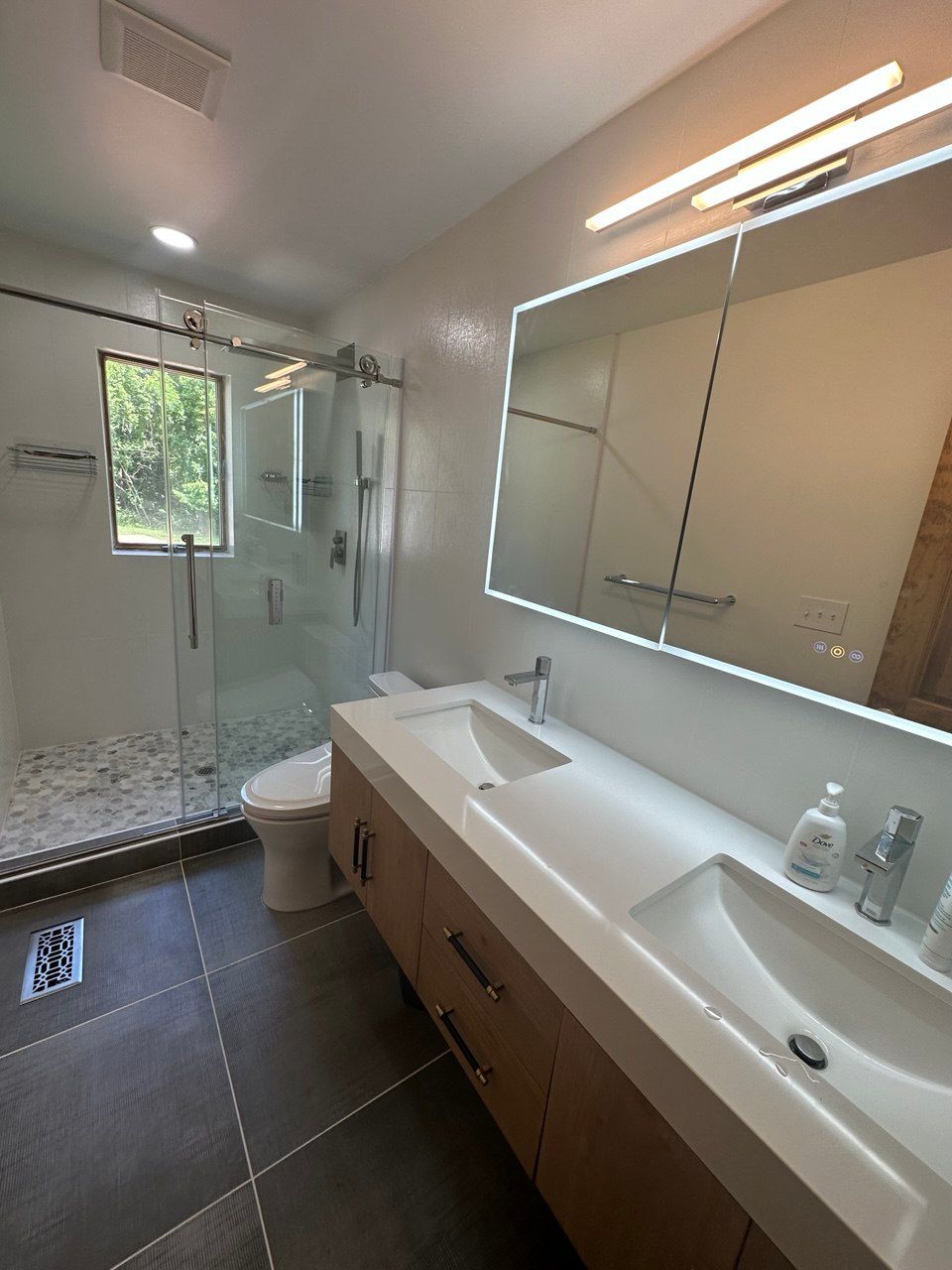 Bathroom remodel in Finksburg with tub converted to shower, frameless barn-style shower door, double floating vanity, LED mirror, and tiled wall