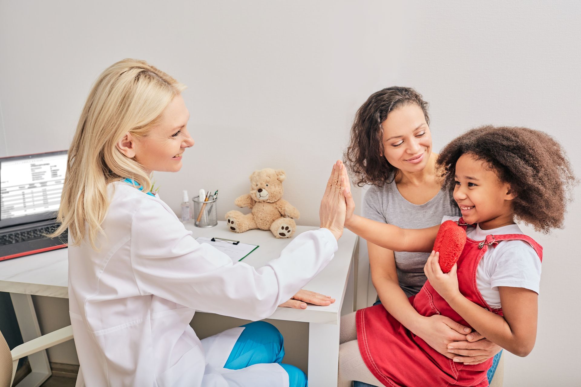 Child high-fives doctor, heart pillow in hand, fostering trust in mental health care.