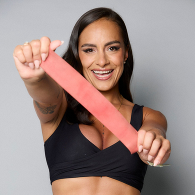 Woman sitting on a stool in black workout clothes against a gray background