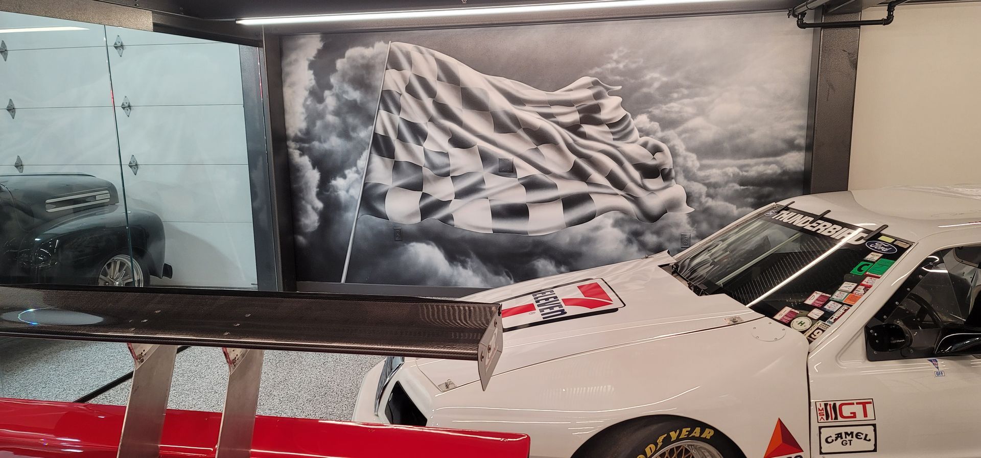 White sports car with a zebra-patterned hood mural in an indoor display.