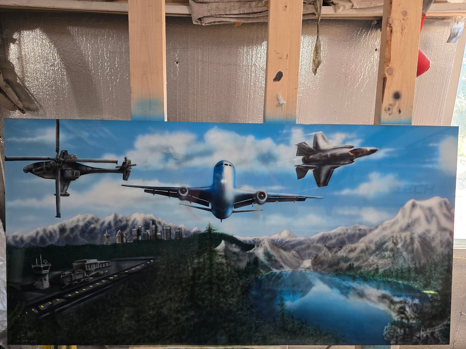 Three fighter jets flying over a mountain lake and forest landscape under a blue sky