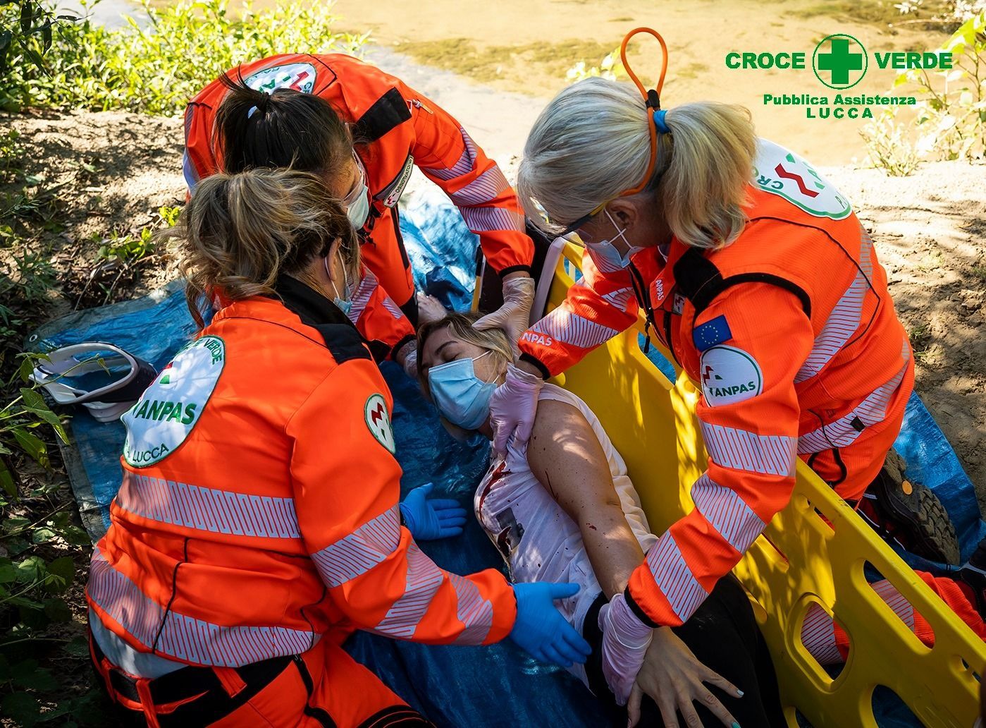 volontari protezione civile mentre assistono una donna sdraiata e priva di sensi