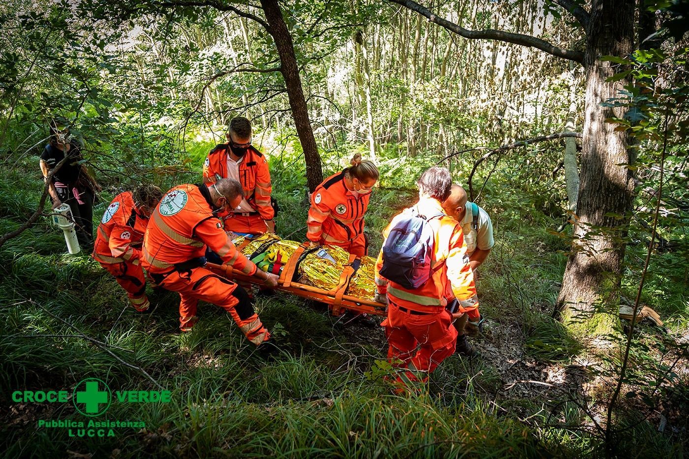 trasporto di una persona con barella da parte di vari volontari immersi nel verde