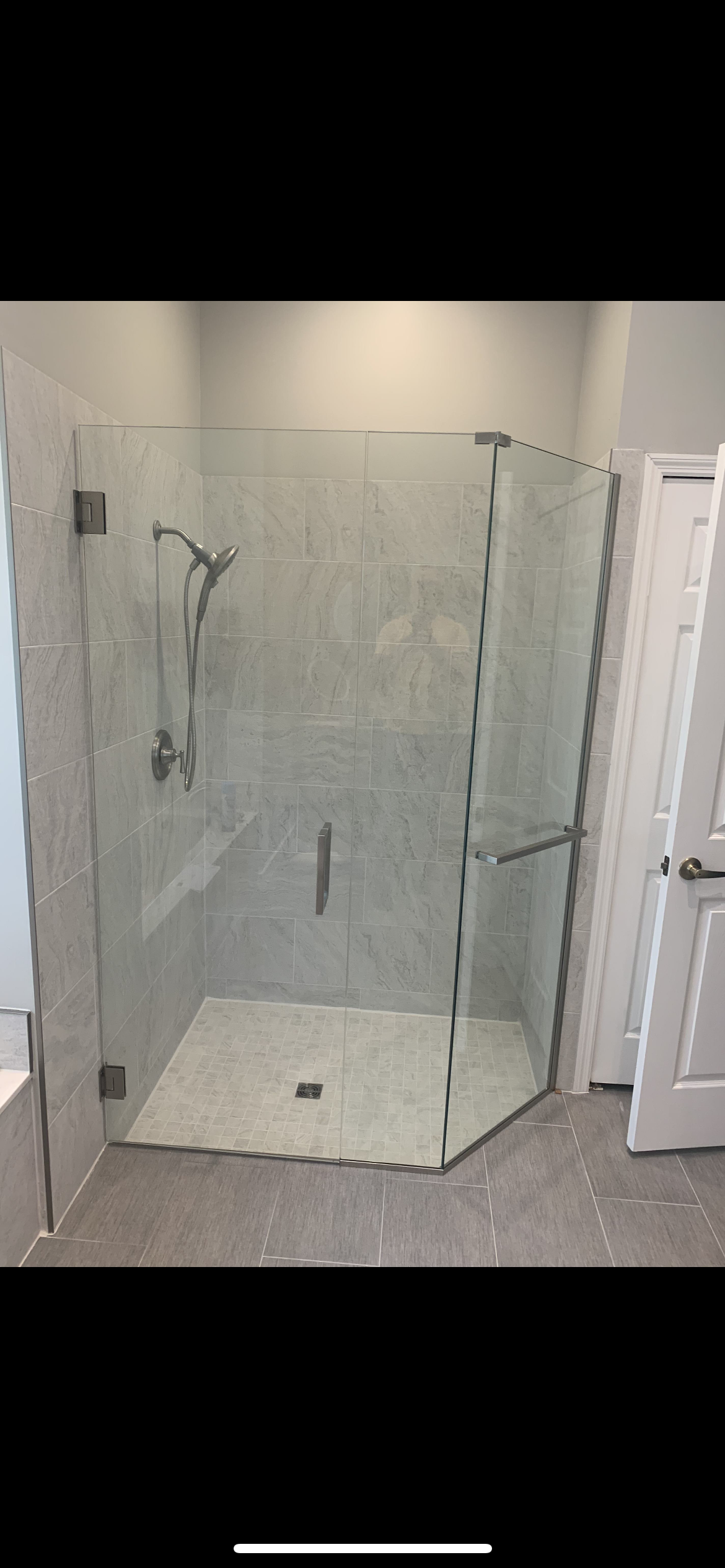 Glass shower enclosure in a bathroom with tiled walls and floor.