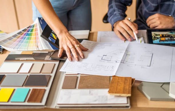 Hands over blueprints and samples, discussing interior design options.