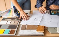 Hands over blueprints and samples, discussing interior design options.