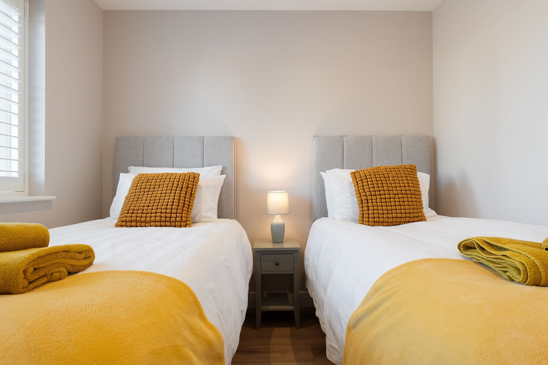 A bedroom with two twin beds and a nightstand.